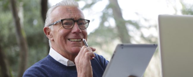 Image of white haired man using electronic devices.