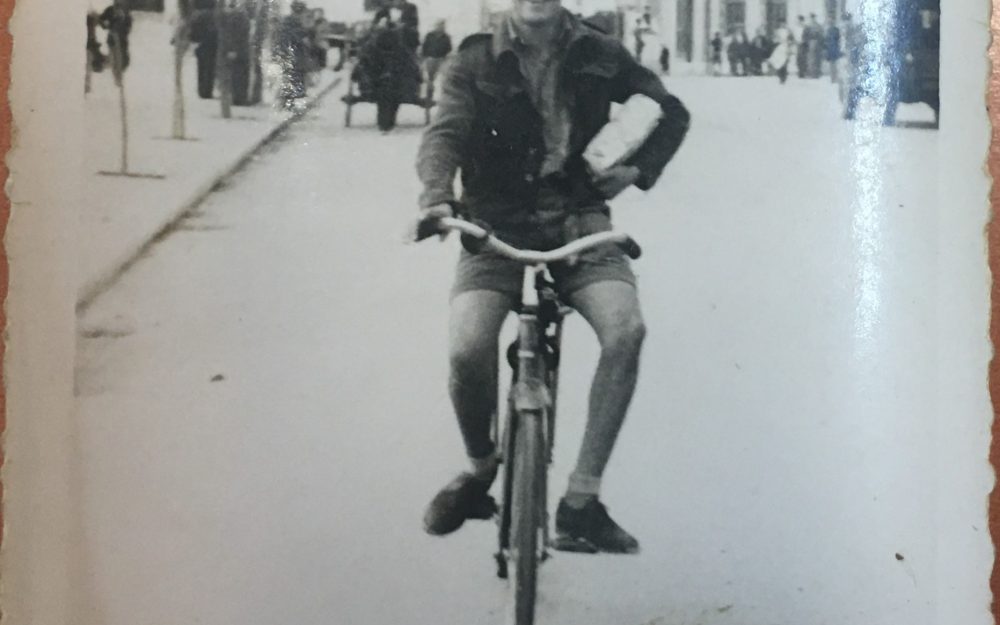 Black and white image of man on bicycle.