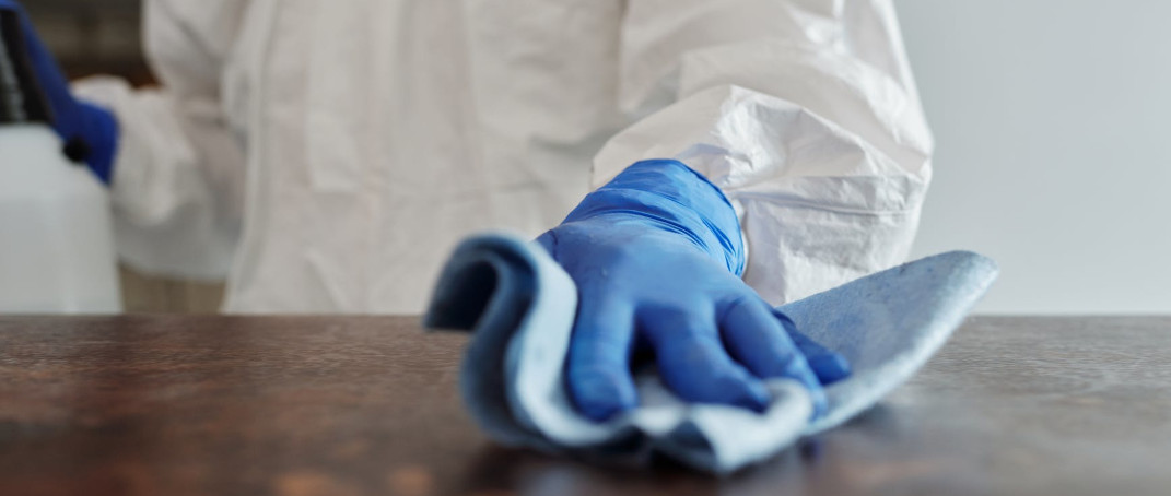 Blue gloved hand disinfecting.