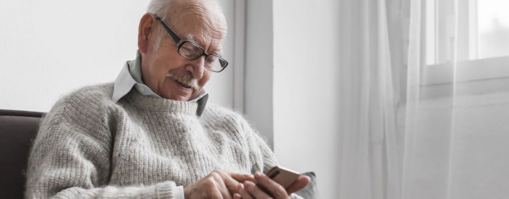 An older man reading news on his smartphone.