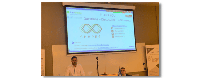 Photo from the 2022 IEEE Energy Conference (ENERGYCON), 9 -12 May 2022. Presenter: Andreas Andreou standing in front of a large projecter with paper title shown.
