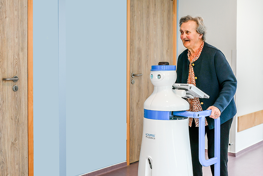 Image of an elderly woman walking with a robot.