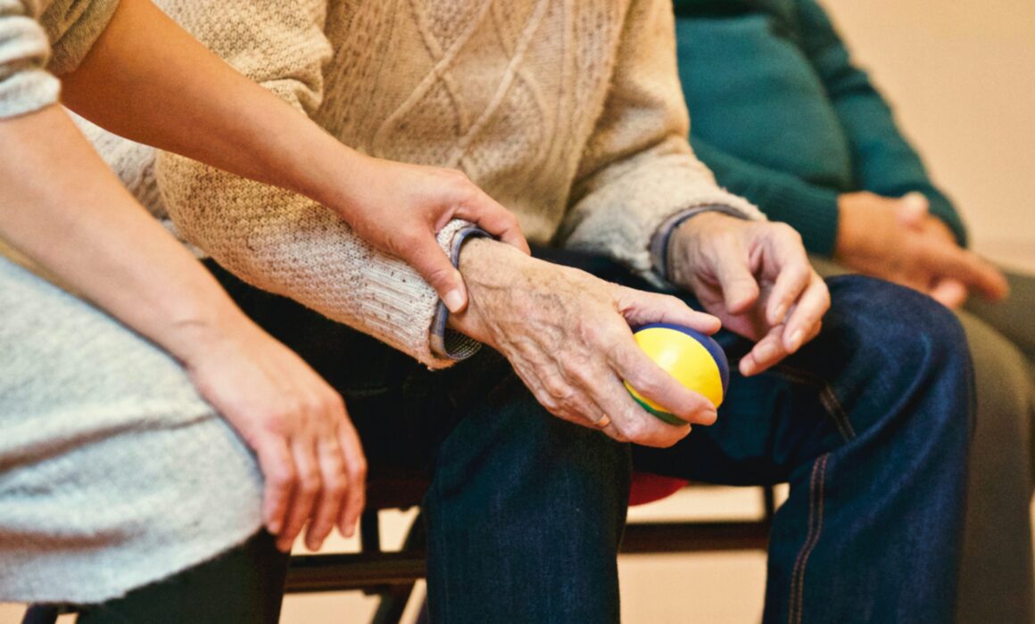 Image of a woman holding an older mans hand in a comforting manner.