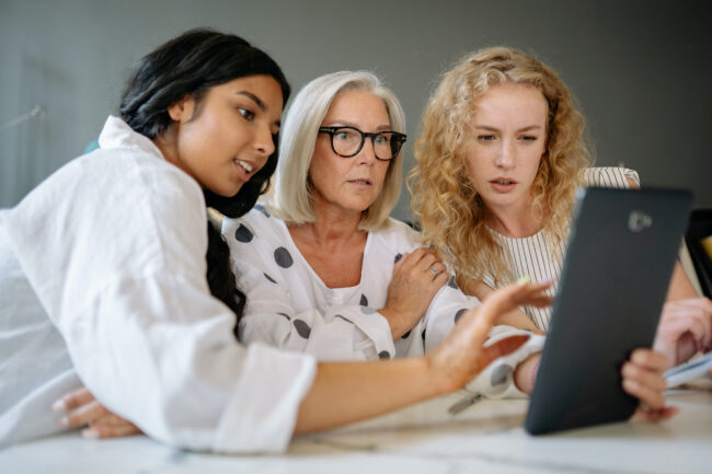 Three women looking at a touch screen computer.