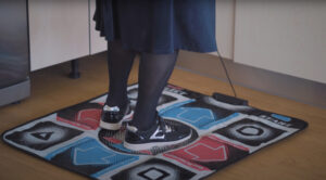 In the image you can see the feet of an elderly woman on the dance mat of the DanceMove digital solution, developed by the SHAPES project.
